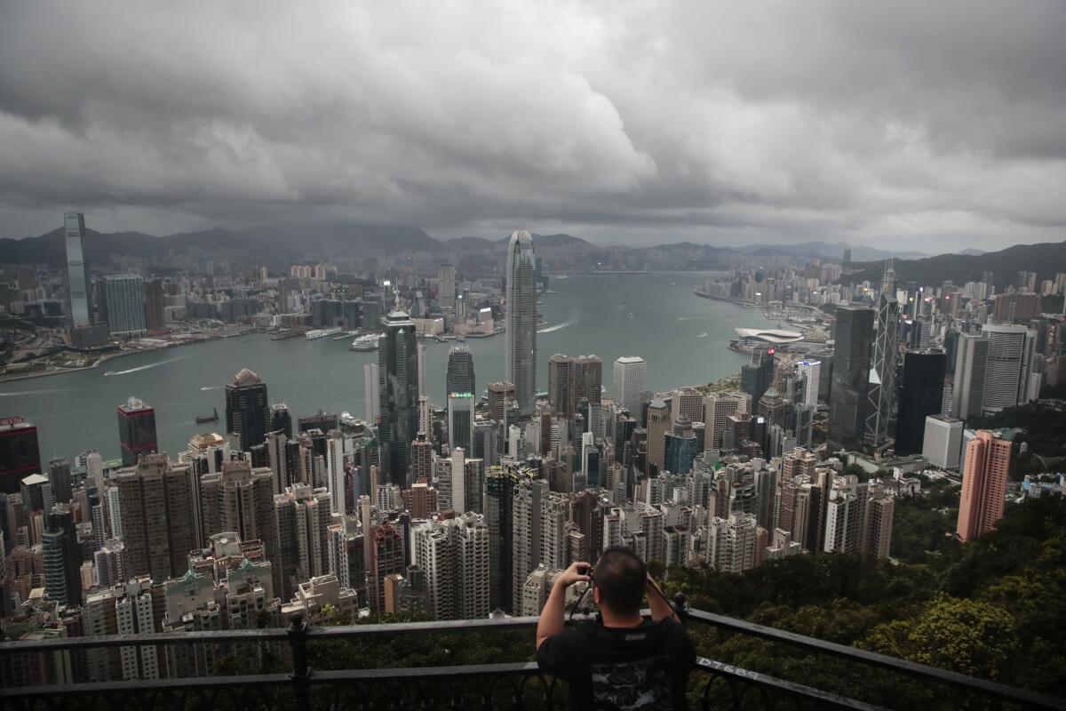 FILE - In this Sept. 1, 2019, file photo, a visitor sets up his camera in the Victoria Peak area to photograph Hong Kong's skyline. Travelers arriving in Hong Kong from China will no longer need to quarantine, Hong Kong’s top official said Tuesday, Sept. 7, 2021, easing curbs imposed after summer outbreaks of the coronavirus on the mainland. (AP Photo/Jae C. Hong, File)