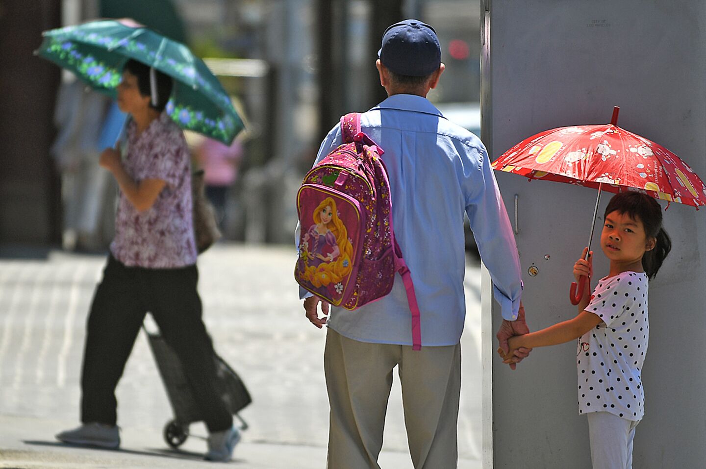 In Chinatown, pedestrians use umbrellas to shield themselves from the sun in 91 degree weather on Friday.