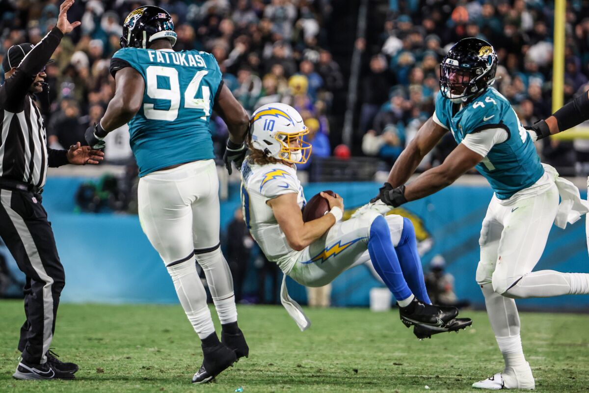 Le quart-arrière des Chargers, Justin Herbert, est projeté au sol par le secondeur des Jaguars de Jacksonville, Travon Walker.