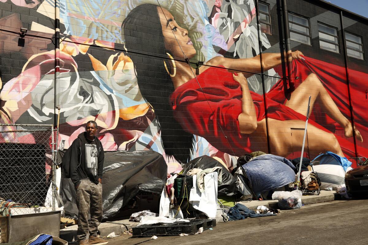 A homeless man stands in front of a row of tents in Los Angeles' Skid Row.