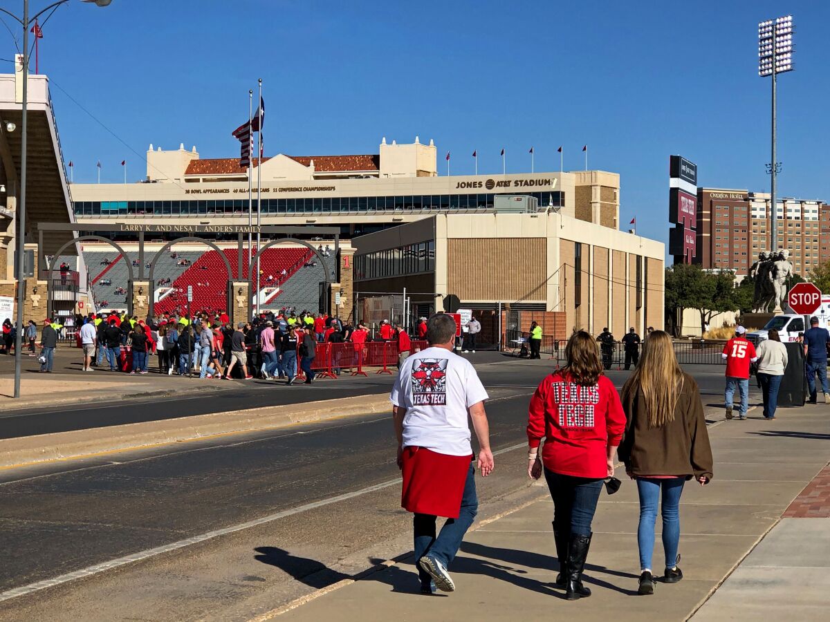 People in red Texas Tech gear walk toward an entrance to the football stadium