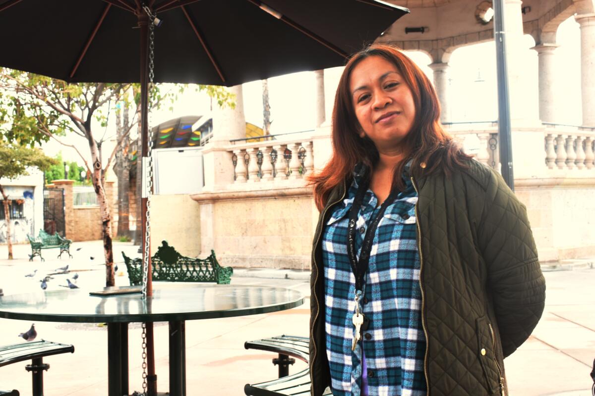 A woman standing near a picnic table in a plaza