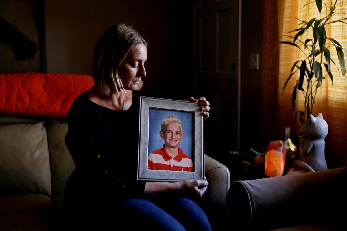 A seated woman holds a photo of a boy.