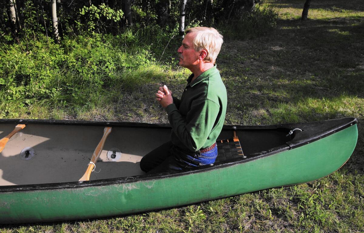 Gary Ferguson kneels in the canoe in which he and his wife, Jane, crashed in rapids along the Kopka River in Ontario, Canada.