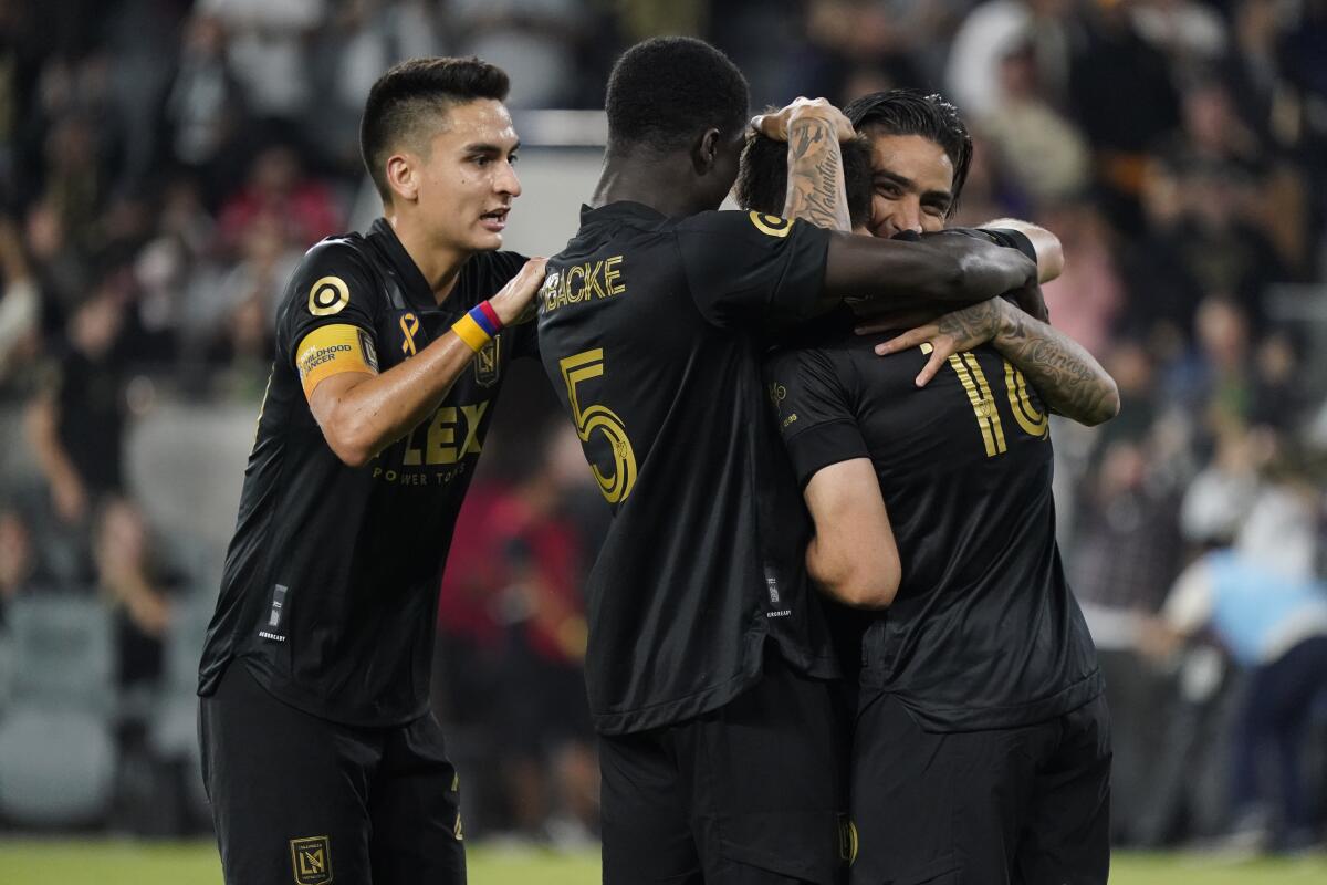 Los Angeles FC forward Danny Musovski, right, is hugged by teammates.