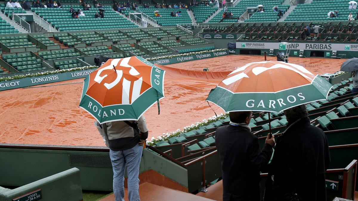 Spectators check out a court at Roland Garros after French Open play was postponed Monday.