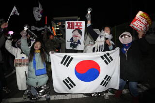 People hold a white flag with red-and-blue colors in a circle at the center and other signs