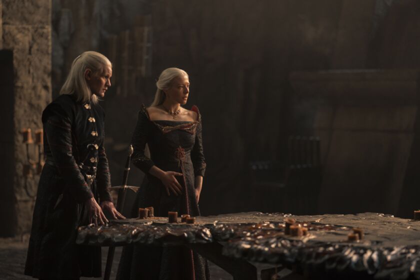 Two blond royals standing by a large stone table