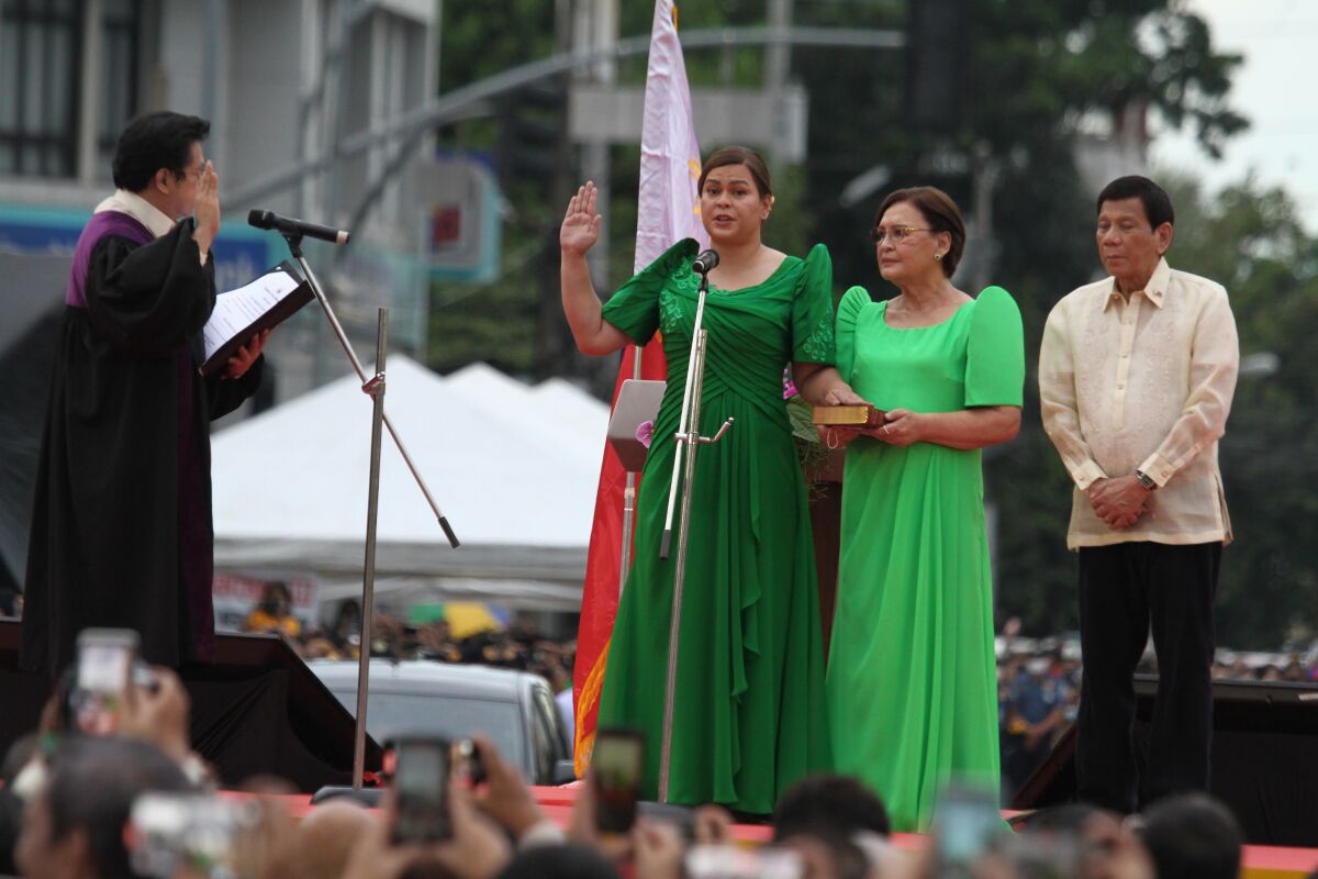 Sara Duterte, wearing a long, green dress, raises her right hand.