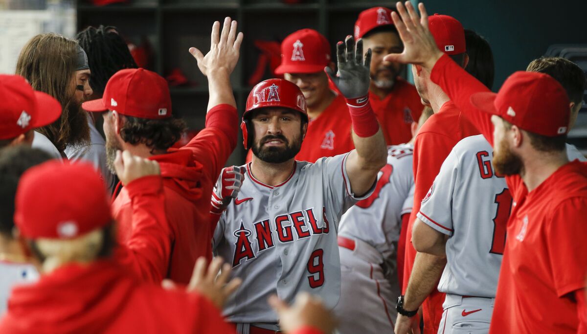 Los Angeles Angels' Adam Eaton (9) is congratulated in the dugout by teammates after hitting a solo home run during the third inning of a baseball game against the Texas Rangers, Thursday, Aug. 5, 2021, in Arlington, Texas. (AP Photo/Brandon Wade)