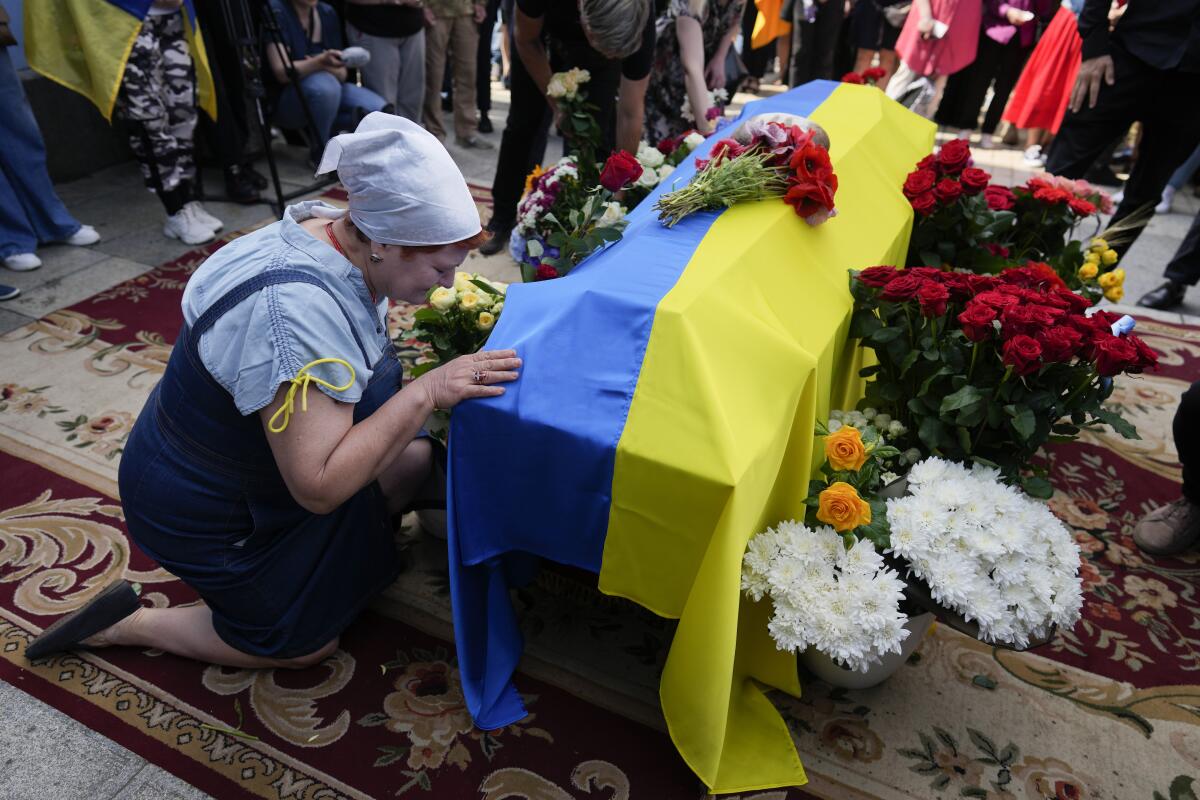 Una mujer se arrodilla junto al féretro del activista y soldado ucraniano Roman Ratushnyi 