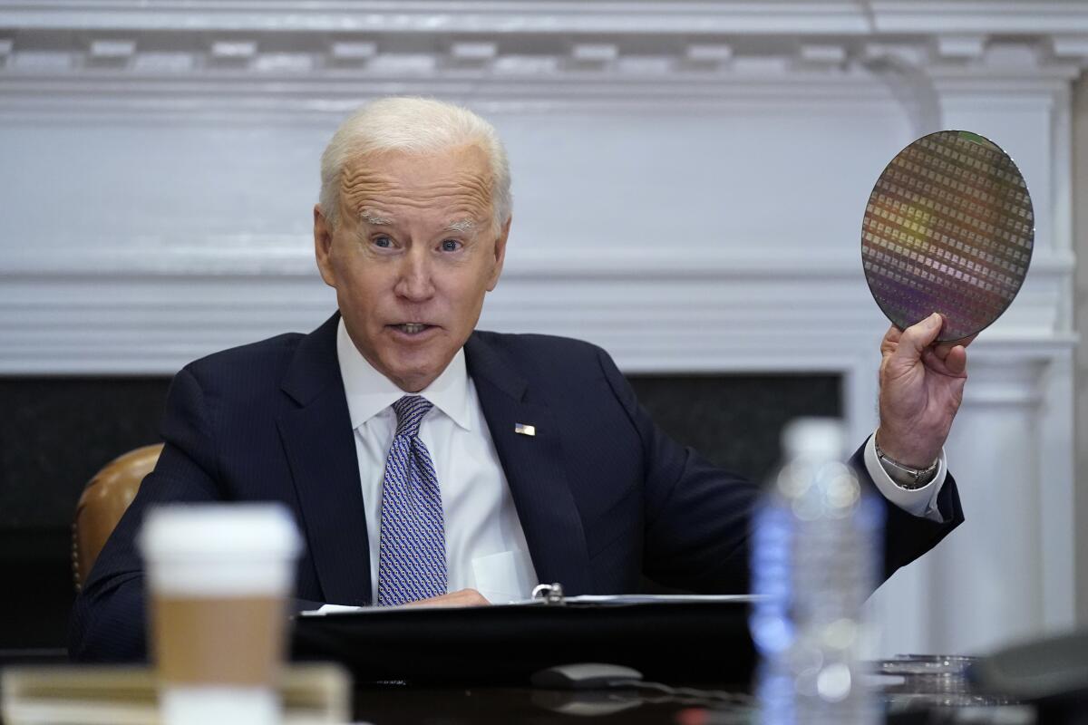 President Biden holds up a silicon wafer as he participates virtually in a meeting at the White House.  