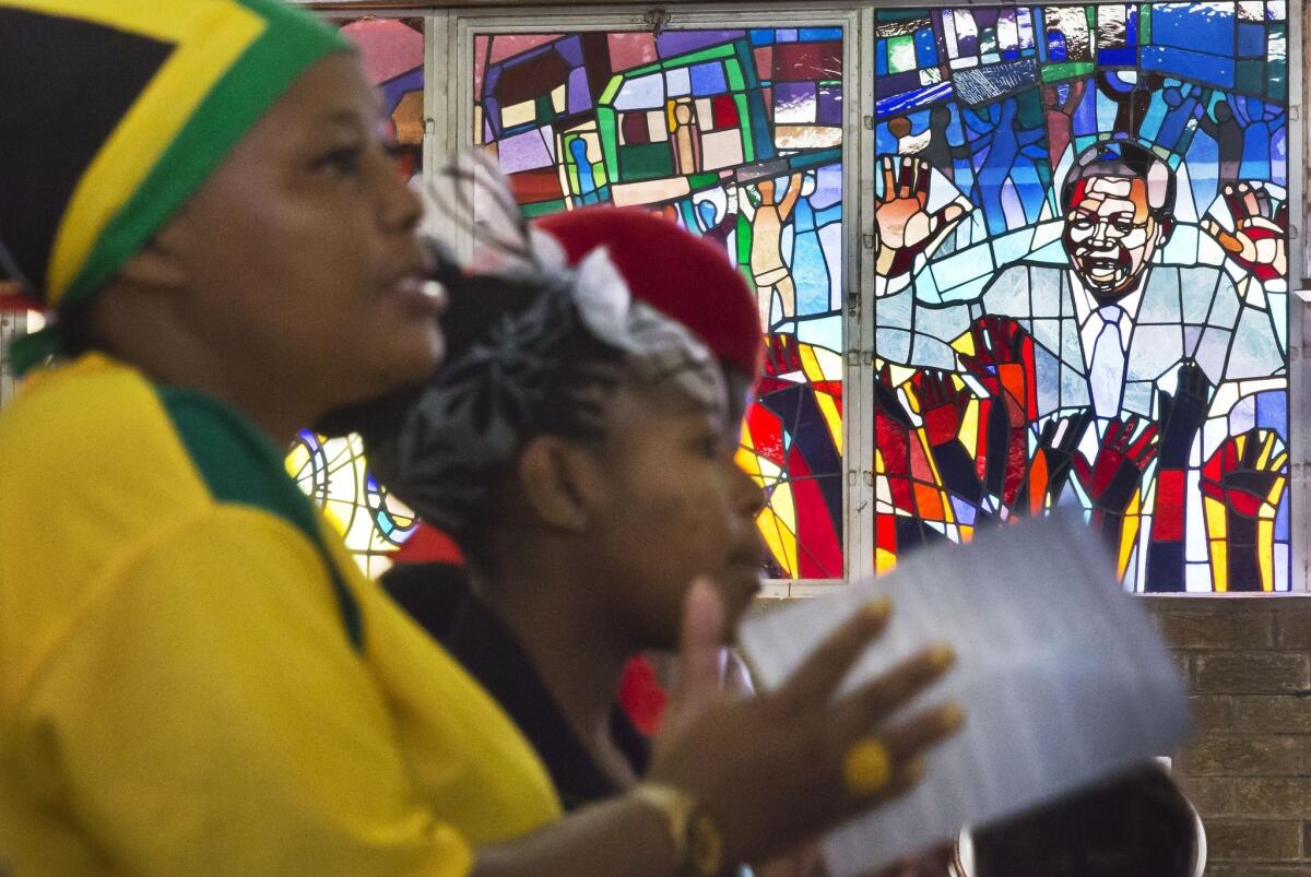 Mourners sit beneath a stained-glass window of Nelson Mandela during morning Mass in his memory at the Regina Mundi church in Soweto, South Africa, which became one of the focal points of the anti-apartheid struggle.
