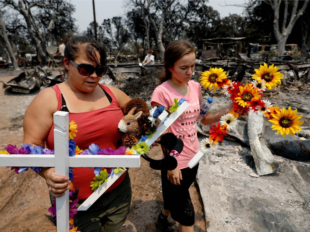 Granddaughter Amanda Woodley, left, of Palo Cidro, and cousin Emilly Belzer carry three crosses to be placed on the property of grandfather Ed Bledsoe. Bledsoe's wife, Melody Bledsoe, and his great-grandchildren, Emily Roberts, 5, and James Roberts, 4, were killed when their Redding home burned.