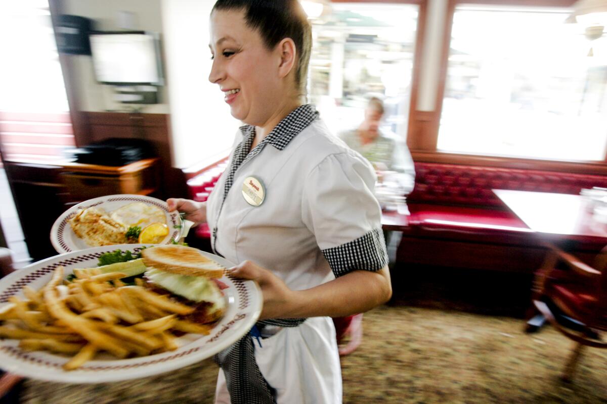 A server in a retro uniform carries plates of food