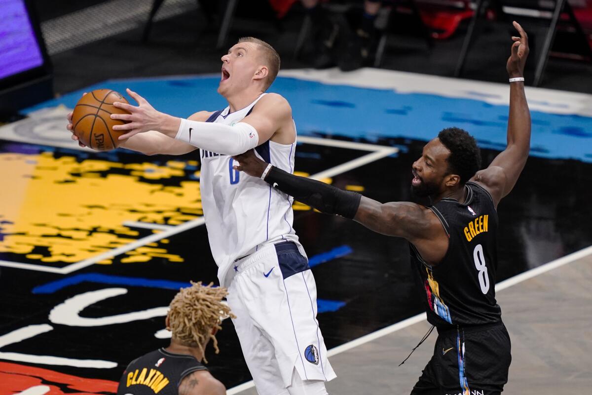 El pívot letón Kristaps Porzingis, de los Mavericks de Dallas, encesta frente a Jeff Green, de los Nets de Brooklyn.