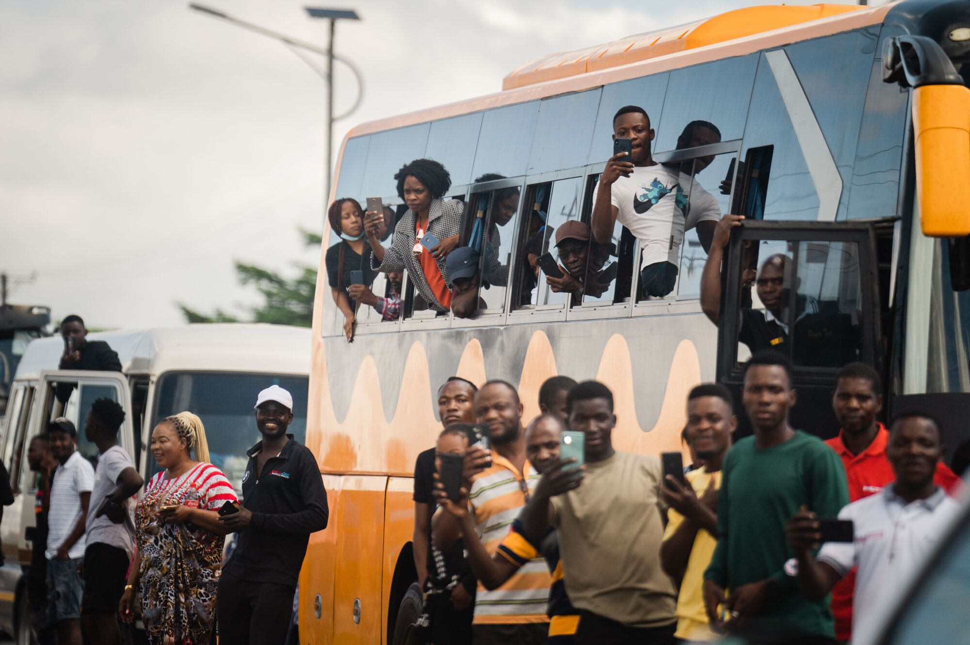 People line the streets and take photographs of U.S. Vice President Kamala Harris' motorcade in Zambia.