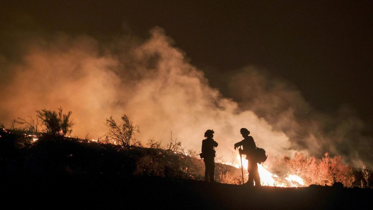 Firefighters keep watch on the Holy fire burning in the Cleveland National Forest in Lake Elsinore on Aug. 9. Researchers have expanded a health-monitoring study of wildland firefighters after a previous study found health declines as the fire season progressed.