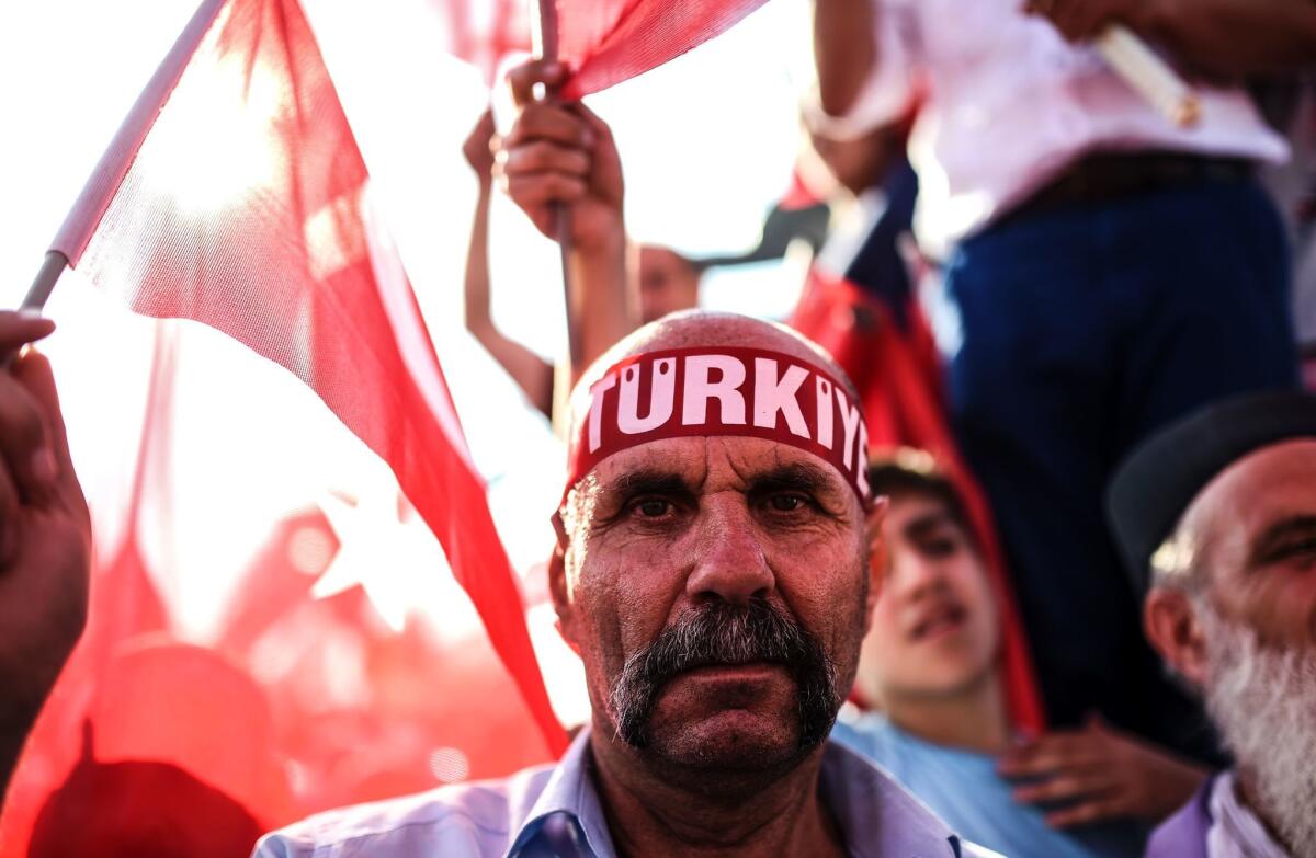A man wears a headband reading "Turkey" as demonstrators wave flags during a rally in Istanbul on Aug. 7, 2016, against the failed military coup on July 15.