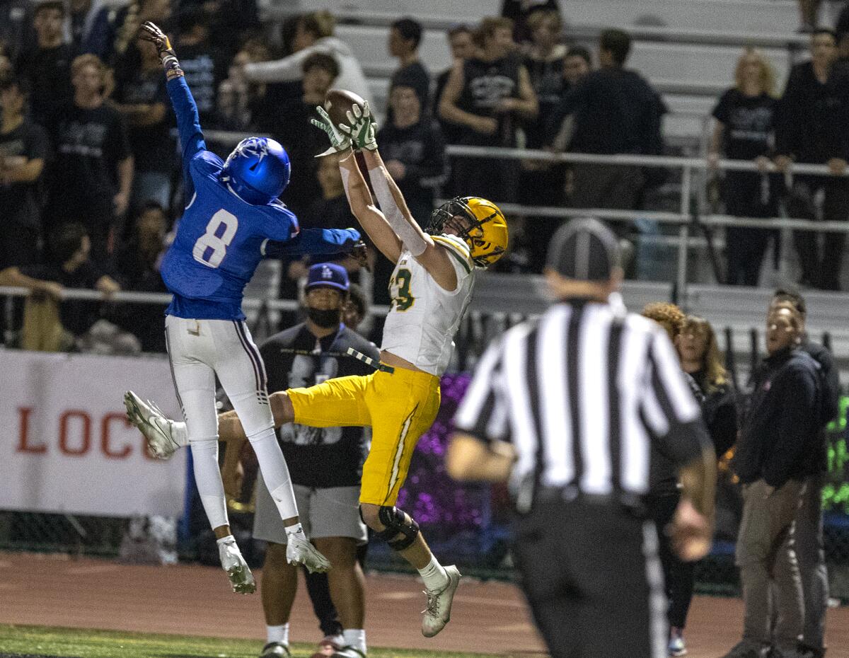 Edison's Tyler Hampton makes a catch over Los Alamitos' Ethan O'Connor during a Sunset League game at Boswell Field.