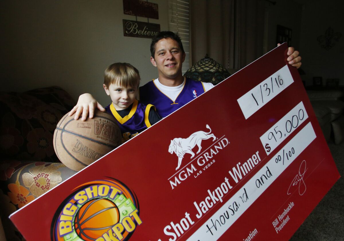 David Moya and his son Aaron are shown at his home in Oakdale, Calif. with the $95,000 check he won after sinking a half court shot during a Lakers game on Jan. 3.