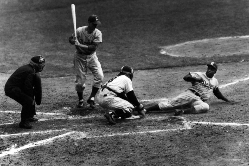 Jackie Robinson safely steals home under the tag of Yankees catcher Yogi Berra in the eighth inning of the 1955 World Series opener at Yankee Stadium. The Dodgers would win the championship in seven games, the first in franchise history and only title for Brooklyn.