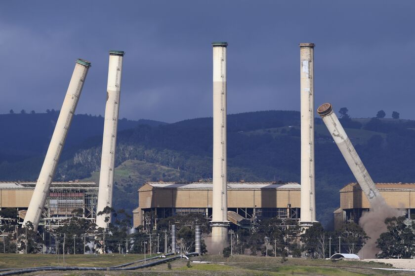 Some of the coal-burning Hazelwood Power Station's eight chimneys begin to topple as they are demolished and the station is decommissioned in Hazelwood, Victoria, on May 25, 2020. The Australian government has taken, on Monday, March 27, 2023, a major step forward in implementing a key climate policy that would force major greenhouse gas polluters to reduce emissions with the minor Greens party pledging their support. (James Ross/AAP Image via AP)