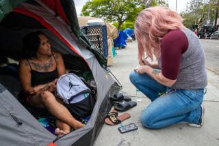 LOS ANGELES, CA - JUNE 07: Monica Quevado, 43, sitting in her tent, gives her information to Rebekah Musser of SHARE who provided her a shelter as Los Angeles City sanitation workers started cleaning-up an encampment along 200 block of S. Venice Blvd., Los Angeles, CA. (Irfan Khan / Los Angeles Times)
