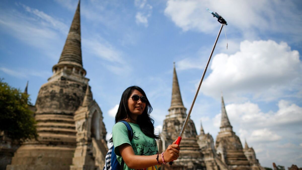A tourist takes a selfie at Wat Phra Si San Phet, one of the many temples in the ancient historical city of Ayutthaya, Thailand.