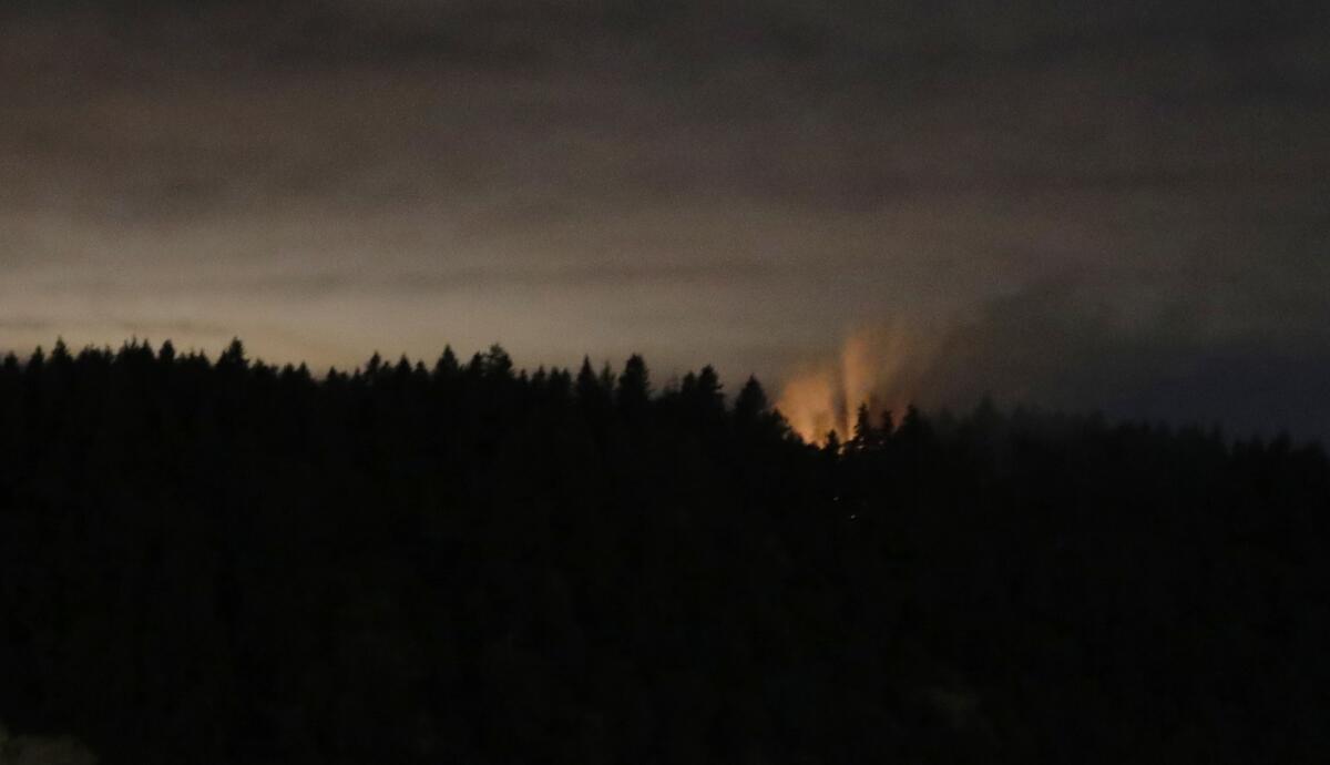 In this long-exposure photo, smoke and an orange glow are seen on Ketron Island after a stolen plane crashed.