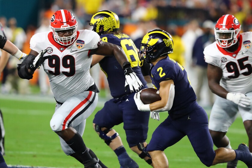 Georgia Bulldogs defensive lineman Jordan Davis (99) pursues Michigan Wolverines running back Blake Corum (2) and tackles him for a loss in the second quarter of the 2021 College Football Playoff Semifinal between the Georgia Bulldogs and the Michigan Wolverines at the Orange Bowl at Hard Rock Stadium in Miami Gardens. (Curtis Compton/Atlanta Journal-Constitution via AP)