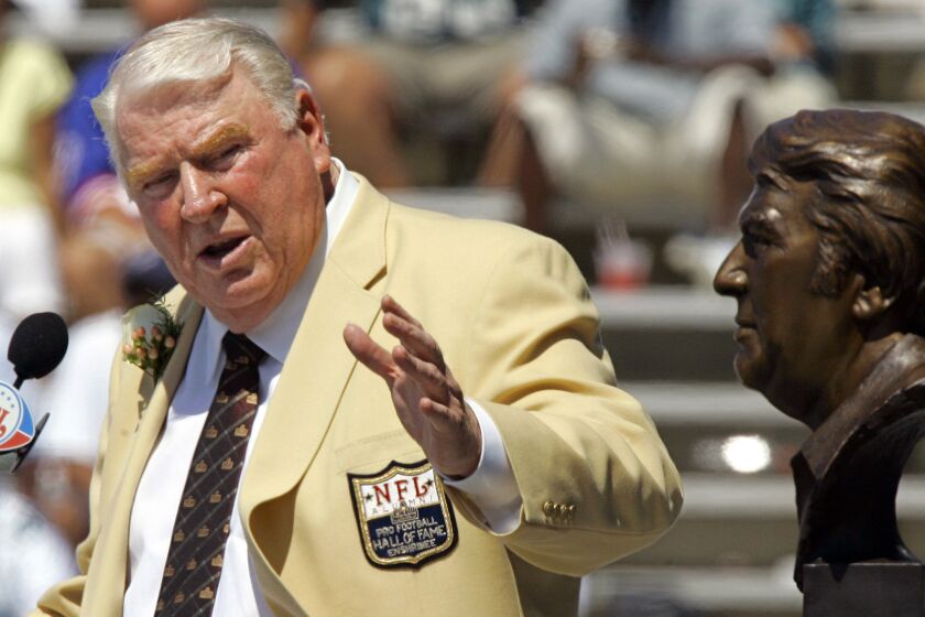 FILE - Former Oakland Raiders coach John Madden gestures toward a bust of himself during his enshrinement into the Pro Football Hall of Fame in Canton, Ohio, Aug. 5, 2006. John Madden, the Hall of Fame coach turned broadcaster whose exuberant calls combined with simple explanations provided a weekly soundtrack to NFL games for three decades, died Tuesday, Dec. 28, 2021, the NFL said. He was 85. (AP Photo/Mark Duncan, File)