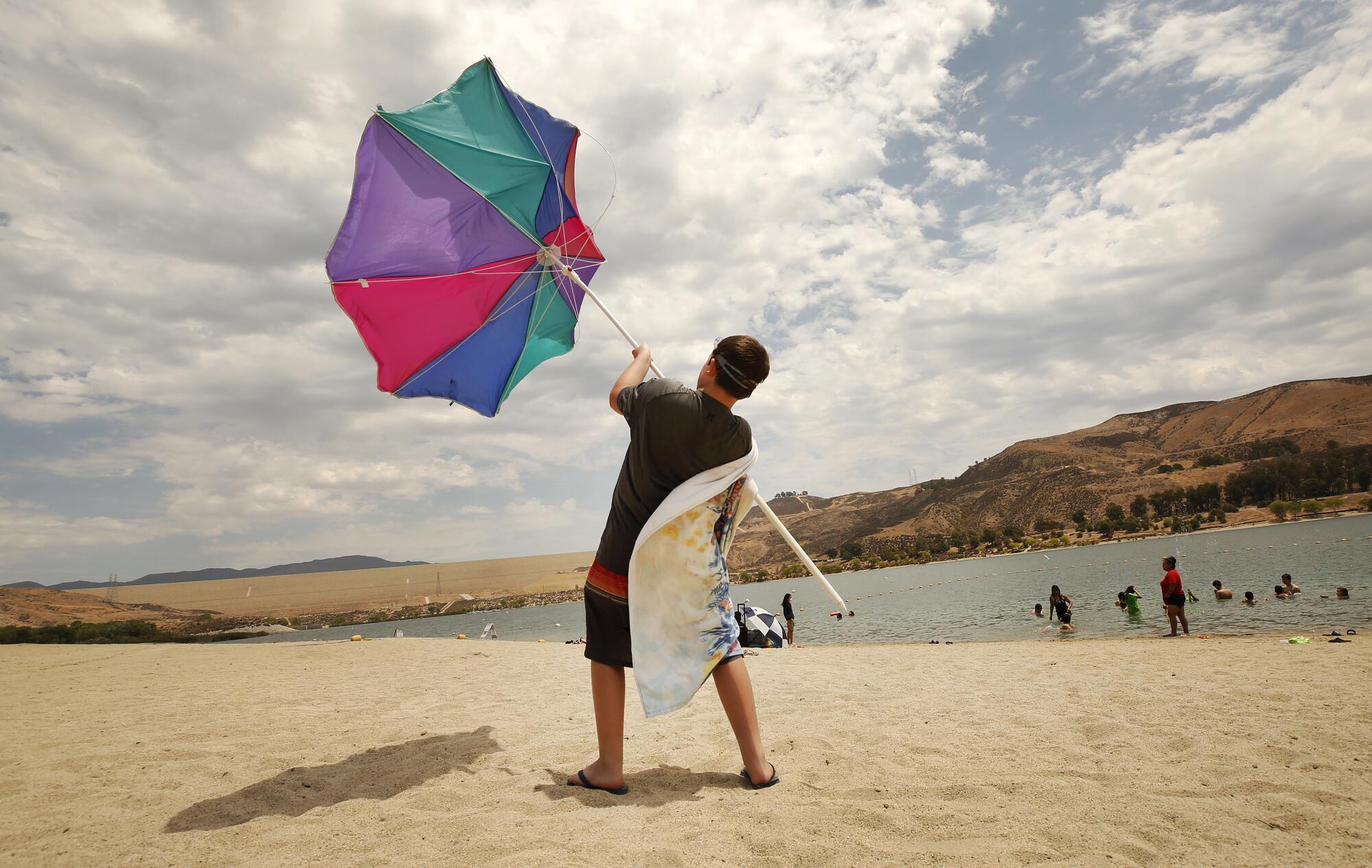Zachary Pruett, 10, catches wind with his umbrella as he was putting it away at Castaic Lake Lagoon.