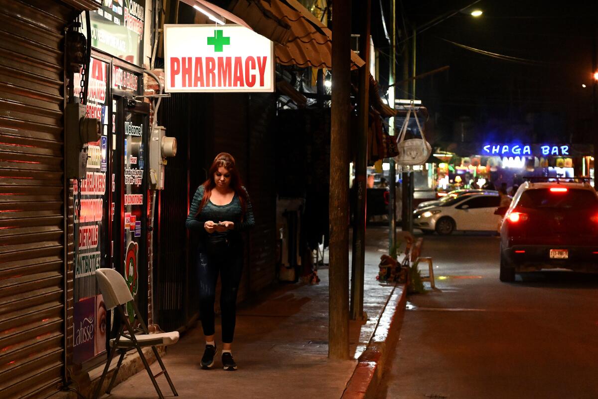 A woman walks past a pharmacy in Cabo San Lucas, Mexico.