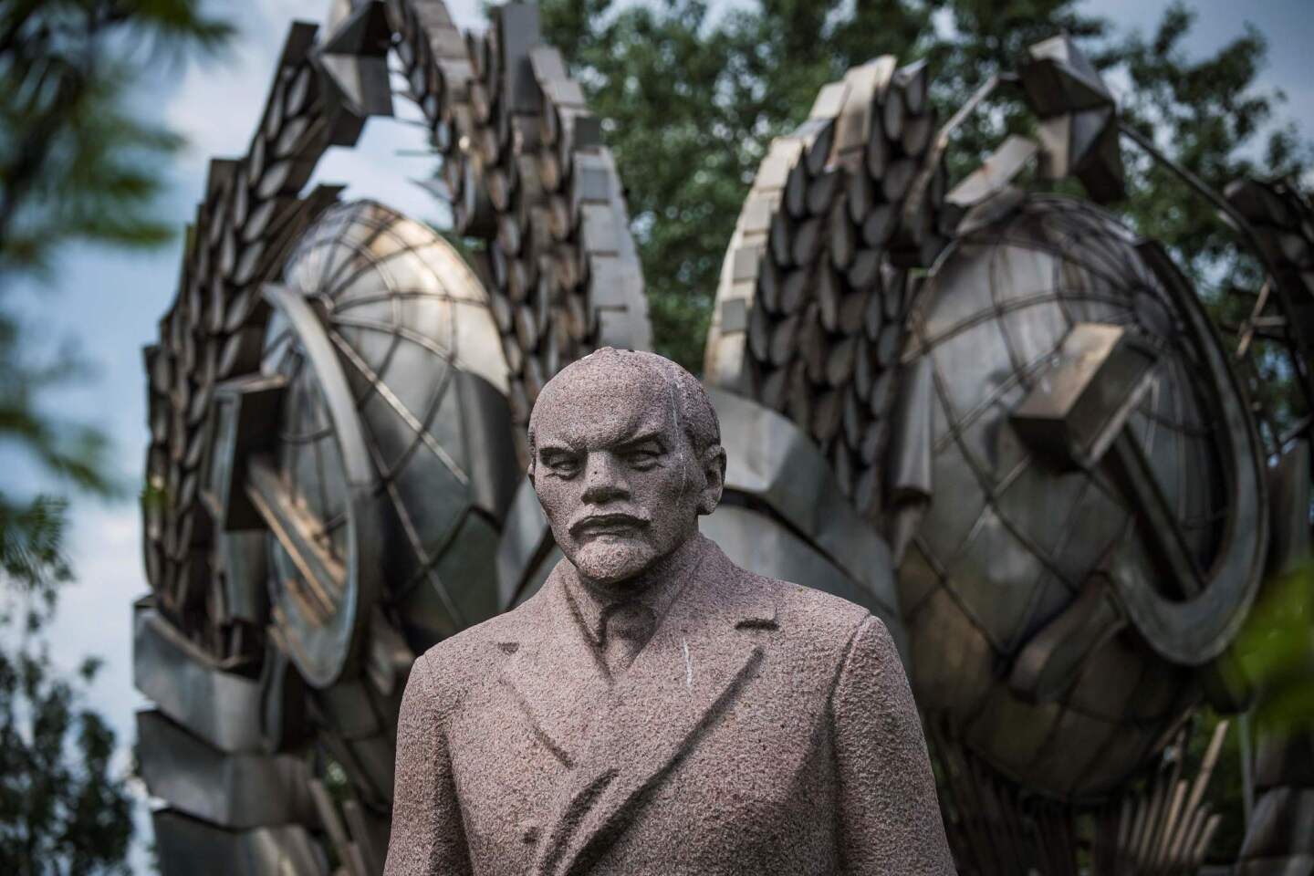 A sculpture of the founder of the Soviet Union, Vladimir Lenin, next to a state emblem of the USSR at the Muzeon Sculpture Park in Moscow.