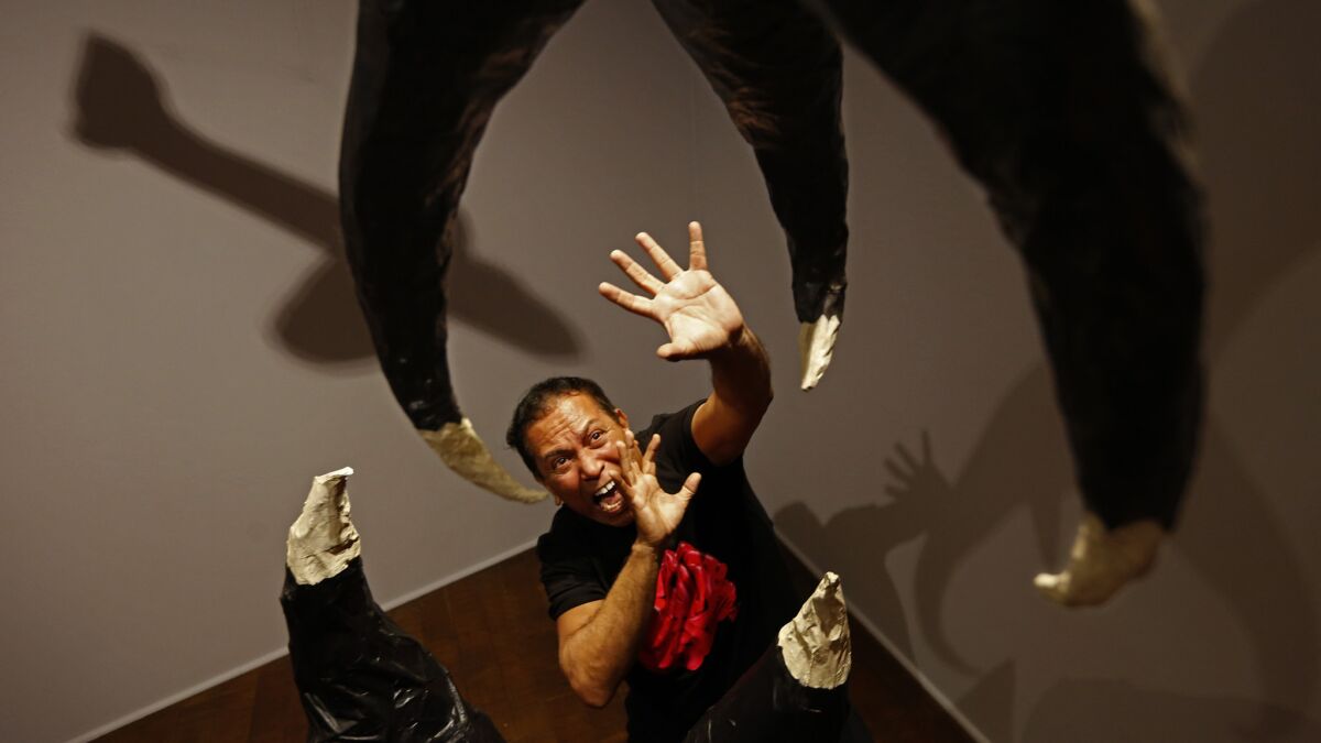 Gronk poses with his sculpture in honor of "The Giant Claw" at the Craft & Folk Art Museum.