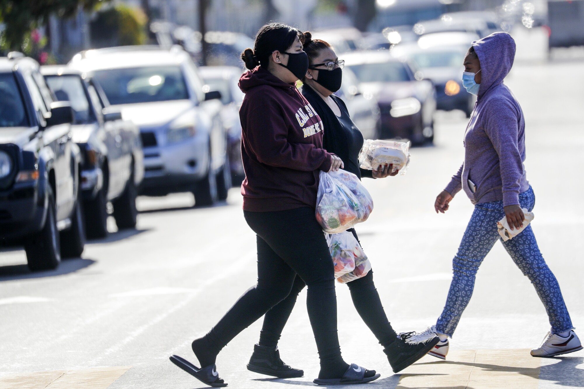 Women carry food bags from the Garfield High distribution site.