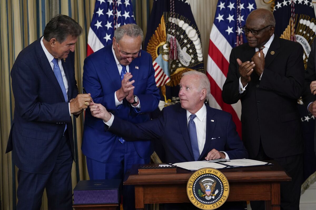 President Joe Biden hands pen to Sen. Joe Manchin.