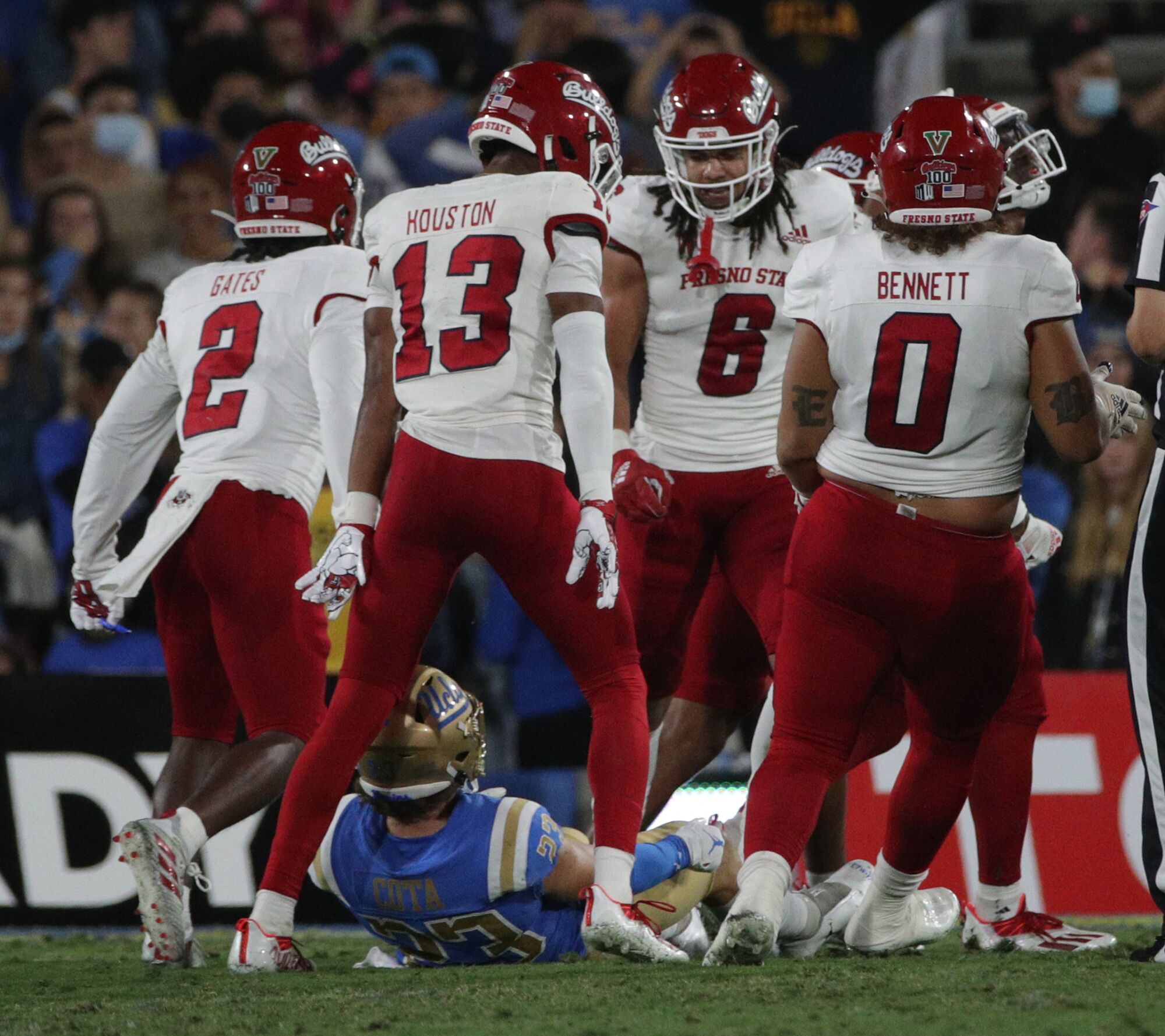  Fresno State defenders stand over UCLA Bruins wide receiver Chase Cota.