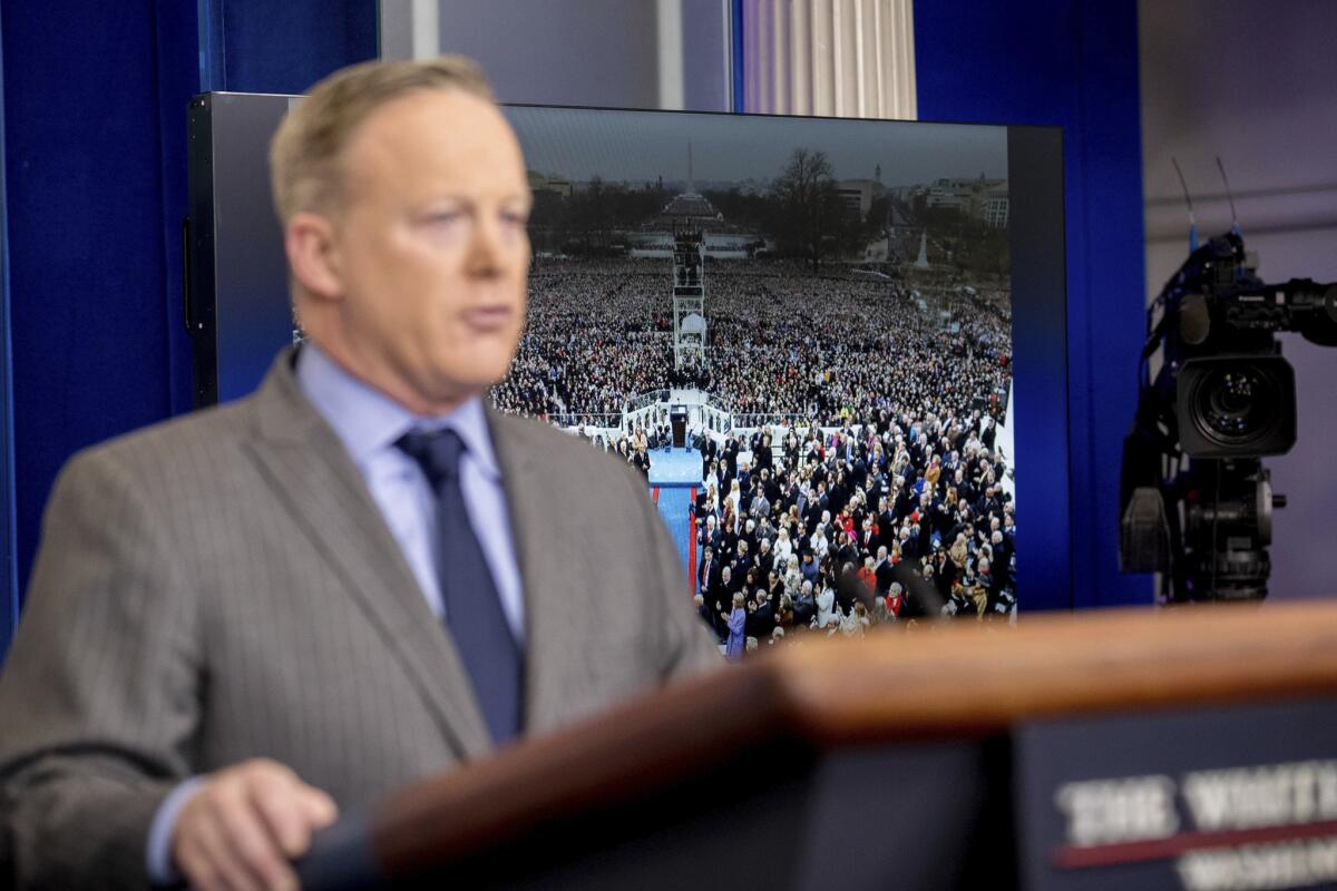 An image of the inauguration of President Donald Trump is displayed behind White House press secretary Sean Spicer as he speaks at the White House, Saturday, Jan. 21, 2017.