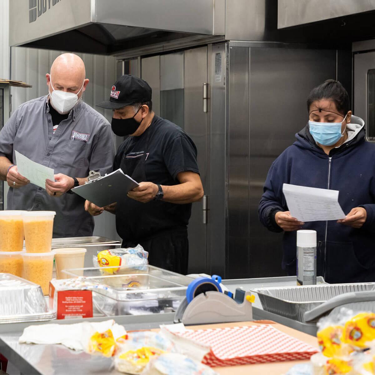 Bill Bracken, left, discusses meals that need to get made with trainees at Bracken's Kitchen.