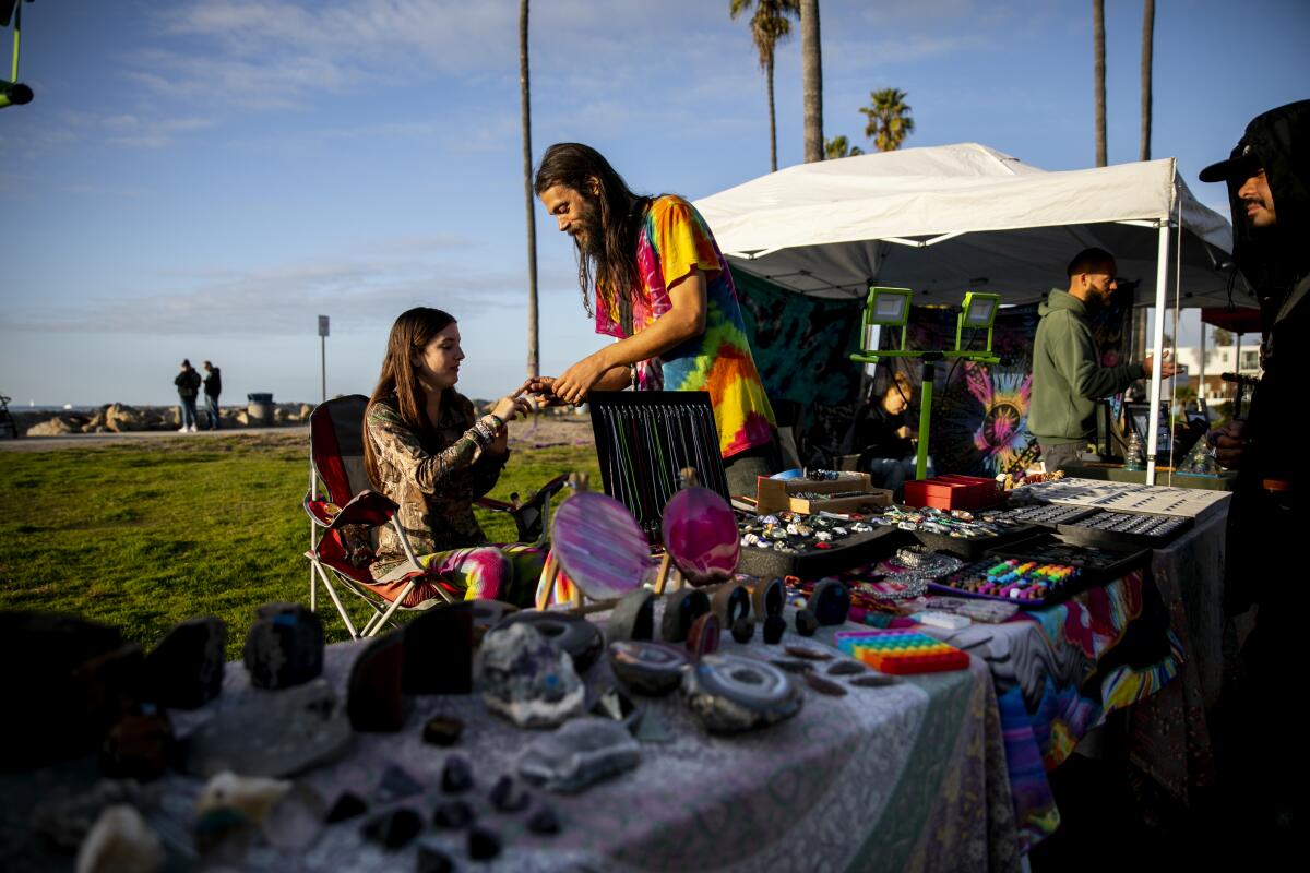 Sidewalk vendors run a stand selling crystals and handmade jewelry near the waterfront in Ocean Beach in December 2021.