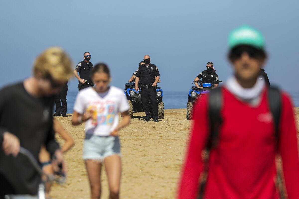 Newport Beach police officers enforce the closure of the beach along the Wedge, a very popular surf spot on July 4.