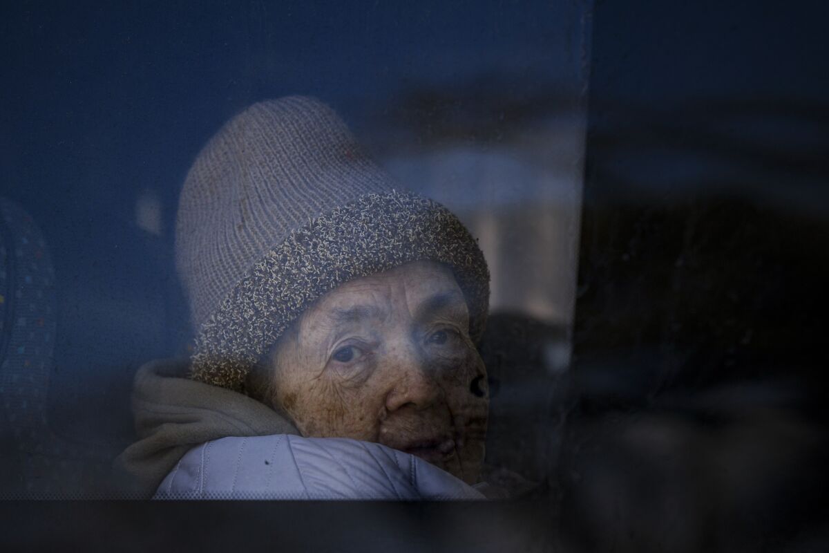 A refugee fleeing the war from neighbouring Ukraine looks out a bus window after crossing the border, at the Romanian-Ukrainian border, in Siret, Romania, Monday, March 14, 2022. (AP Photo/Andreea Alexandru)