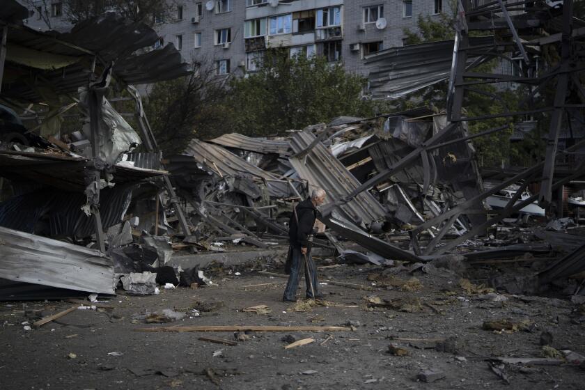 An elderly man walks past a car shop that was destroyed after a Russian attack in Zaporizhzhia, Ukraine, Tuesday, Oct. 11, 2022. (AP Photo/Leo Correa)