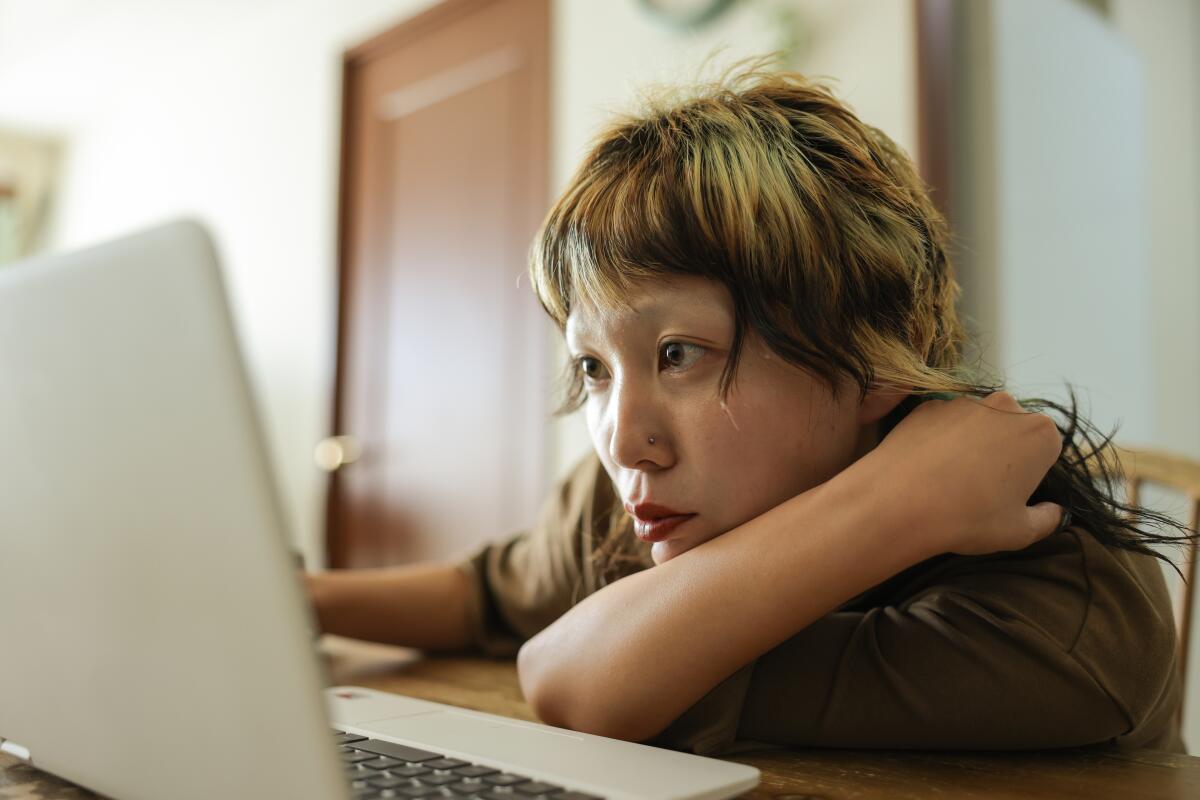 Close up shot of young person at home struggling to find work while searching on their laptop.