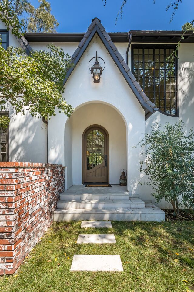 An arched front door and pitched roofline lend a whimsical quality to the house.