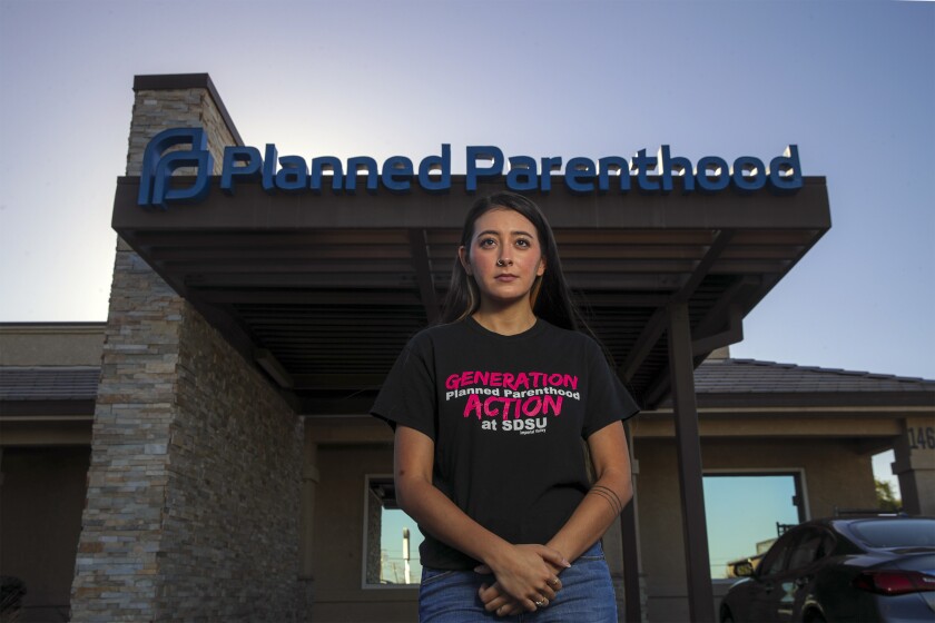 A woman stands in front of a Planned Parenthood building.