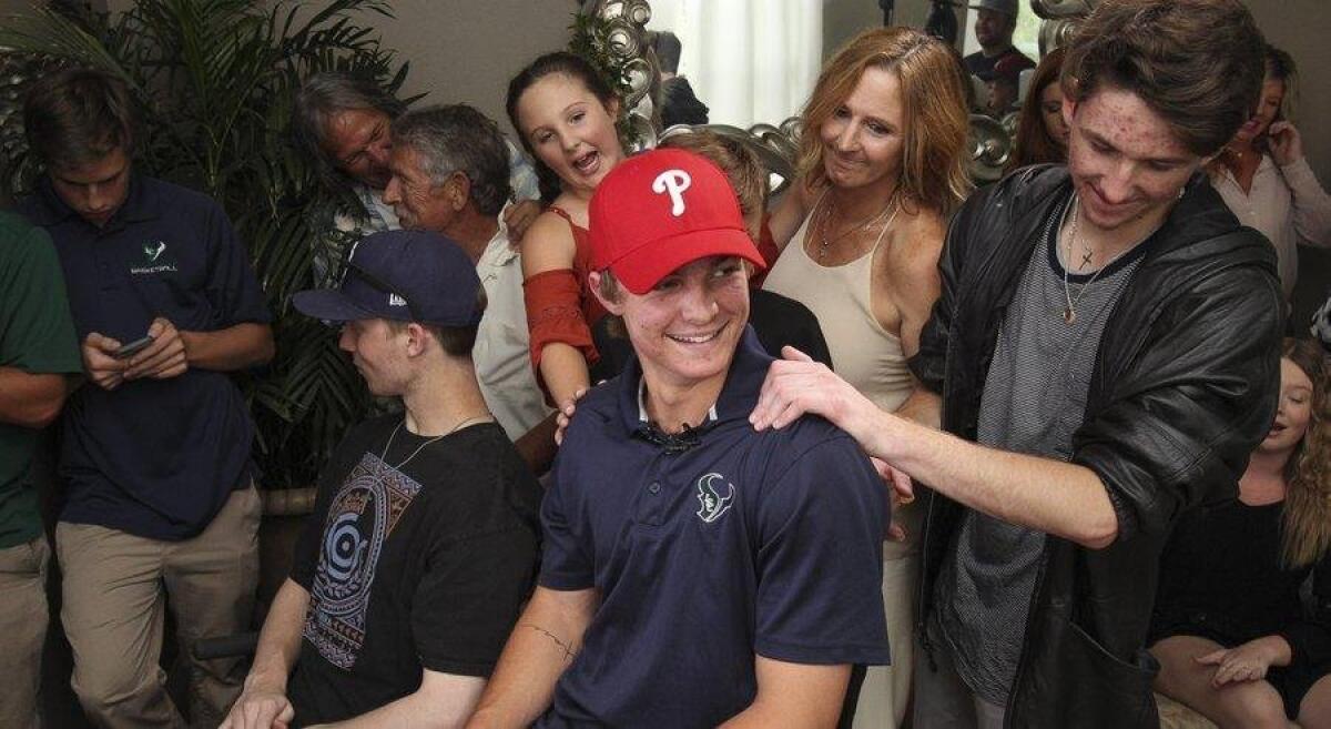 Brother Collin, 16, right, mother Heather, and sister Jordan, 10, touch La Costa Canyon baseball player Mickey Moniak, 18, after it was announced that the Philadelphia Phillies selected Moniak as the No. 1 overall pick in the MLB draft Thursday.