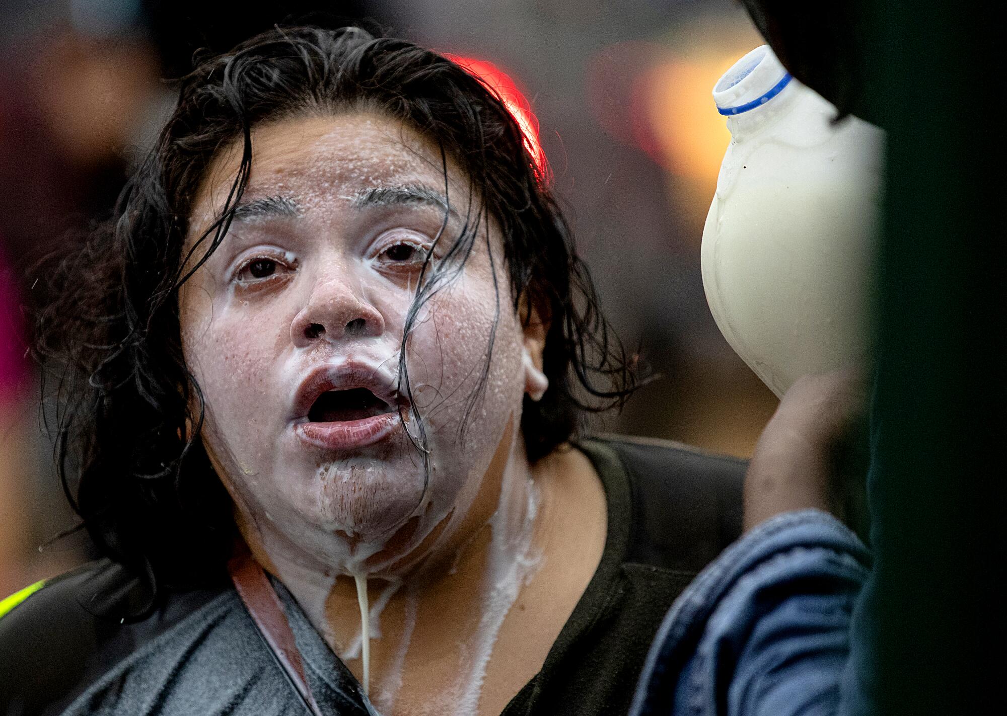 Milk drains from the face of a protester who had been exposed to percussion grenades and tear gas outside a Minneapolis police station.